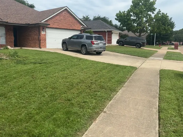 Front lawn with fresh mowing stripes running up to a brick house
